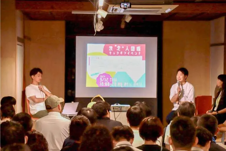 スクリーンの前で対談する男性たち